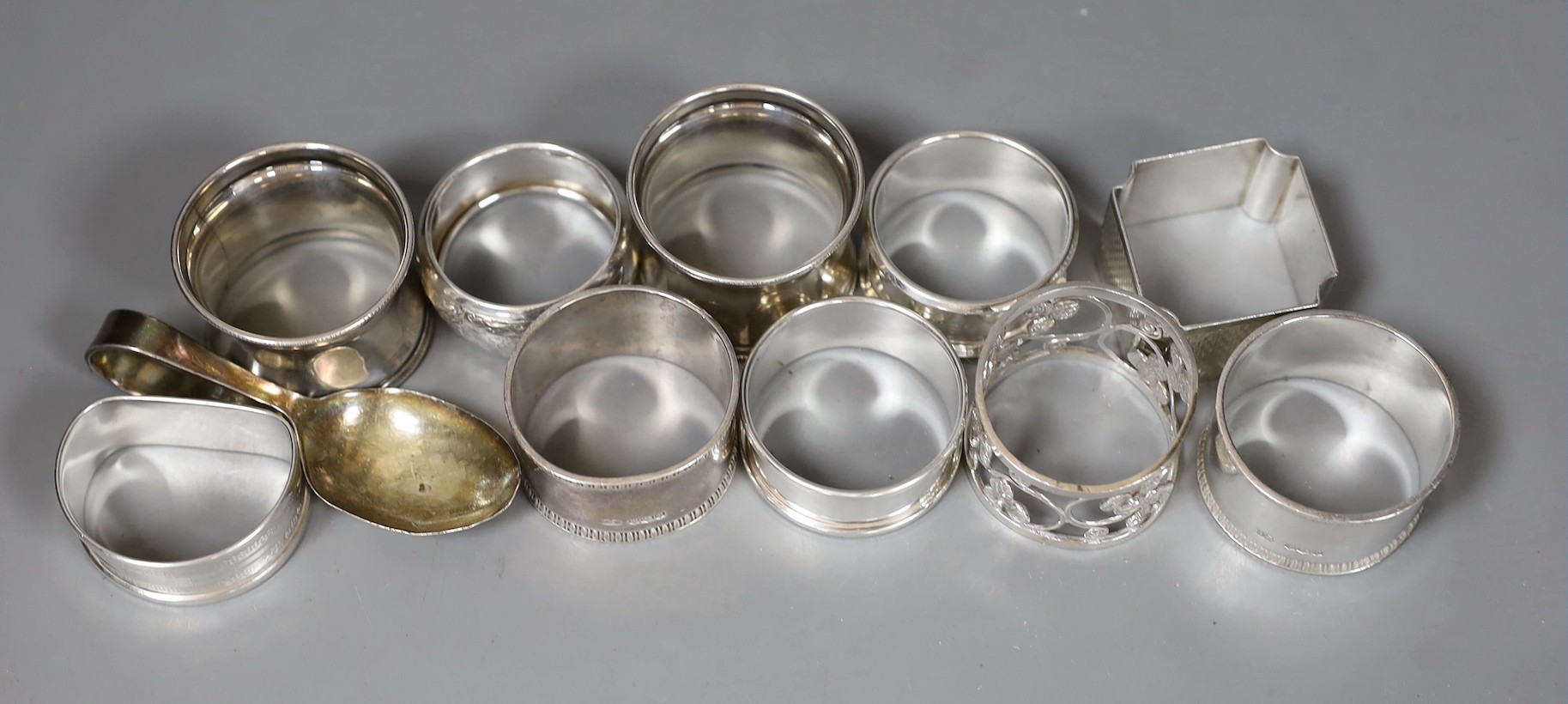 Nine assorted silver napkin rings including a pair of late Victorian and later pair, one other napkin ring and a silver spoon, weighable silver 7oz.